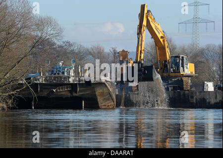 An excavator on a platform clears the Main Danube Canal from stones in Hausen, Germany, 22 January 2011. The canal was first covered with ice, then flooded and now it is filled with tons of stones. Therefore, it remains closed in the section between Bamberg and the sluce Hausen nearby Forchheim. Ships will be allowed to pass as early as the beginning of February. Photo: David Ebene Stock Photo