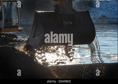 An excavator on a platform clears the Main Danube Canal from stones in Hausen, Germany, 22 January 2011. The canal was first covered with ice, then flooded and now it is filled with tons of stones. Therefore, it remains closed in the section between Bamberg and the sluce Hausen nearby Forchheim. Ships will be allowed to pass as early as the beginning of February. Photo: David Ebene Stock Photo