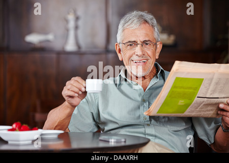 Happy senior man sitting with coffee and newspaper in a café Stock Photo