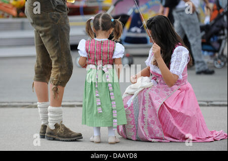 A small girl in traditional dirndl visits the 178th Oktoberfest with two adults on Theresienwiese in Munich, Germany, 22 September 2011. Oktoberfest continues until 03 October 2011 in the Bavarian capital. Photo: ANDREAS GEBERT Stock Photo