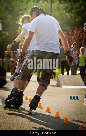 Couple synchronously roller blading through slalom cones. Stock Photo