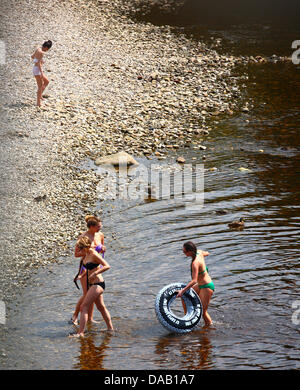 People paddling in the River Wharfe at Ilkley and cooling off on a hot summers day in the UK Stock Photo