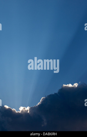 Crepuscular rays shining up from dark cloud after rainstorm Stock Photo