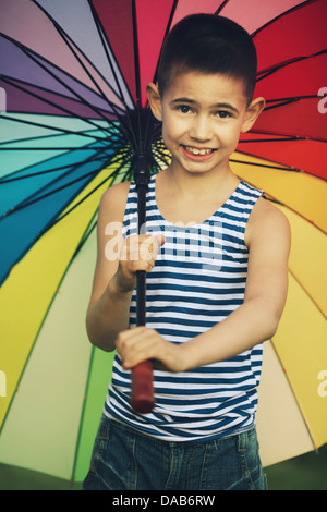 little happy girl with a rainbow umbrella in park Stock Photo