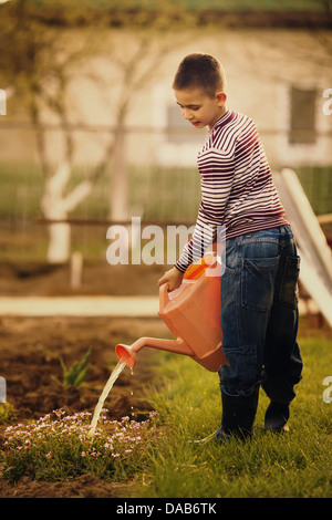 little boy watering flowers in the garden Stock Photo