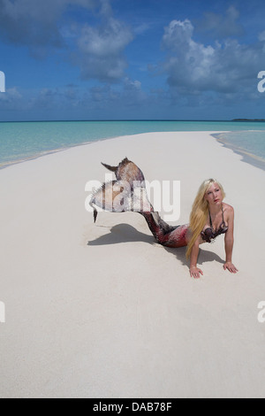 Young blond mermaid laying on a sandbar in the Exuma Cays Nassau, in the Bahama Islands Stock Photo