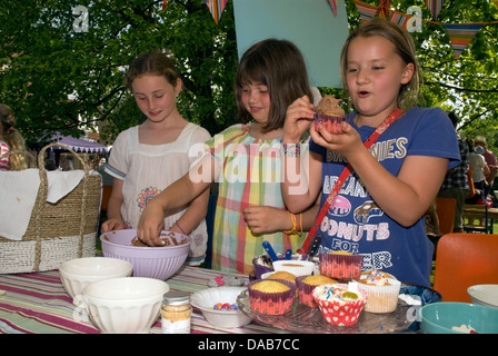 Youngsters at cake stall decorating/icing their own cake at a summer fete, East Meon, Hampshire, UK. Stock Photo