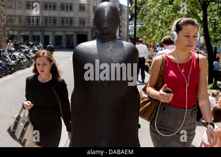 City of London office workers pass one of a pair of leaning figures by Anthony Gormley entitled Parralel Field (1990), part of Sculpture in the City, a summer street art exhibition in the Square Mile, the capital's financial district. Antony Mark David Gormley, OBE, RA (born 30 August 1950) is a British sculptor. His best known works include the Angel of the North, a public sculpture near Newcastle upon Tyne in the North of England, commissioned in 1994 and erected in February 1998. Stock Photo