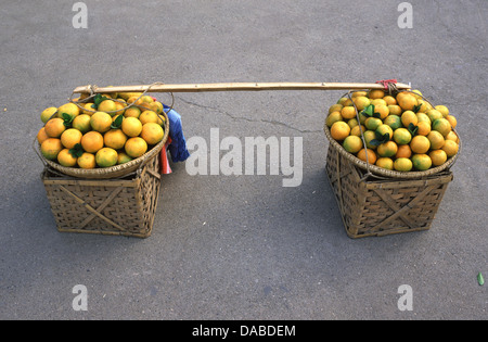 Baskets filled with oranges in a wooden shoulder carrying pole in Haikou, Hainan Province China Stock Photo