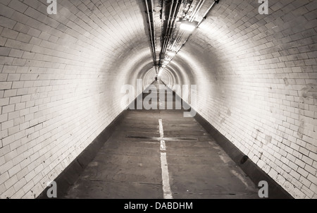 A solitary figure walking under the river Thames in the Greenwich foot tunnel towards the Isle of Dogs in East London Stock Photo