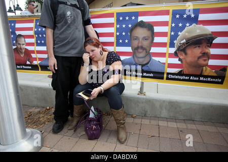 Prescott Valley, Arizona, USA. 9th July, 2013. LAURA MITCHELL, cousin of fallen firefighter GARRET ZUPPIGER, sits in front of Garret's picture and cries. She was comforted by Chris Mitchell. The 19 Granite Mountain Hotshots killed in the Yarnell fire were honored as a group Tuesday at a memorial. Credit:  Krista Kennell/ZUMAPRESS.com/Alamy Live News Stock Photo