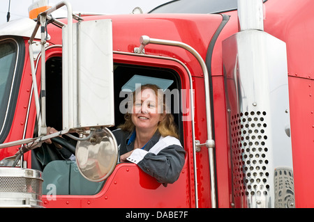 Woman truck driver in the cab of a red semi-truck Stock Photo
