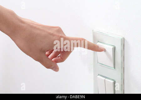 Woman hand turning on the light with a wall switch Stock Photo
