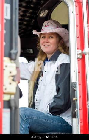 Woman truck driver ready to start her run with a loaded trailer behind a semi-truck. Stock Photo