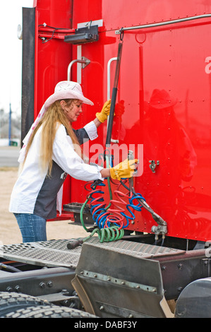 A woman hangs up the air lines after dropping off her trailer. Stock Photo