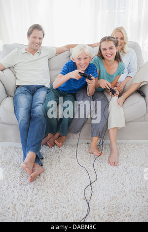 Children playing video games together sitting on the couch Stock Photo