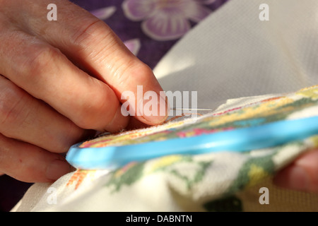 Hands of an old woman busy embroidering Stock Photo