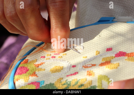 Hands of an old woman busy embroidering Stock Photo