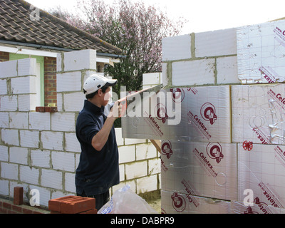 Apprentice builder sawing celotex board to fit a wall Stock Photo