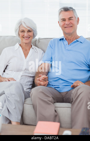 Mature couple hand in hand sitting on a couch Stock Photo