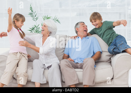 Grandchildren jumping on couch with their grandparents Stock Photo