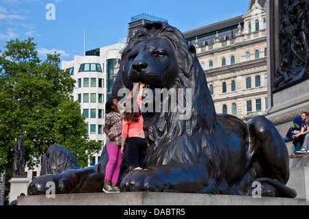 Children Climbing On The Lion Statue, Trafalgar Square, London, England Stock Photo