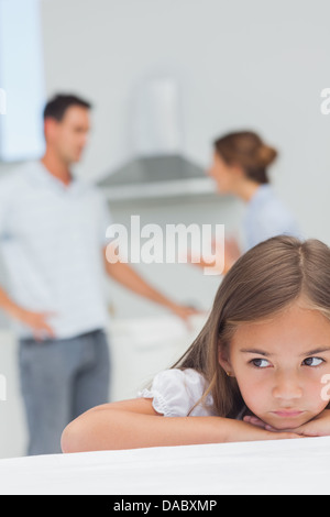 Upset little girl listening to parents who are arguing Stock Photo