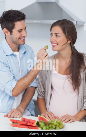 Man giving a grape to his pregnant partner Stock Photo