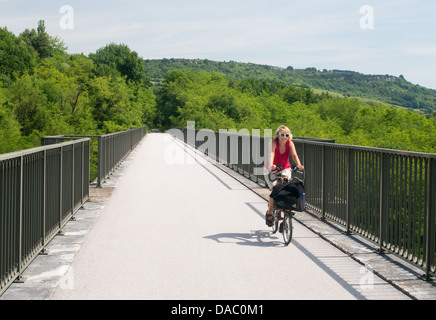 Mature woman cyclist passing over an ex railway viaduct  following a cycle path near Nolay in Burgundy  France Stock Photo