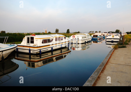 A view of hire boats with reflections moored on the Norfolk Broads in Thurne Dyke, Norfolk, England, United Kingdom. Stock Photo