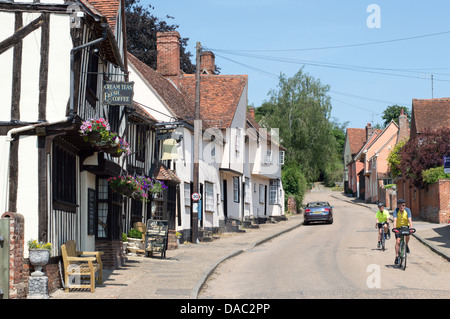 Two cyclists cycling down The Street in Kersey, regarded as the most picturesque village in Suffolk, England. Stock Photo