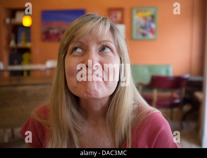 Woman looking up to her right with a smile and lips sealed. Stock Photo