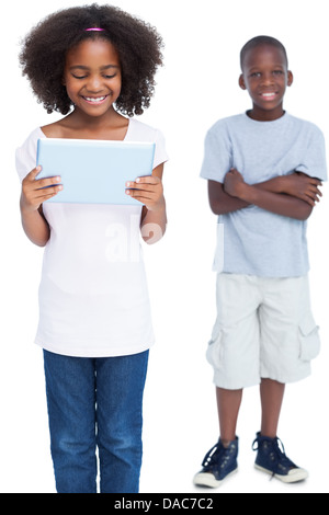 Girl using tablet pc with her brother behind her Stock Photo