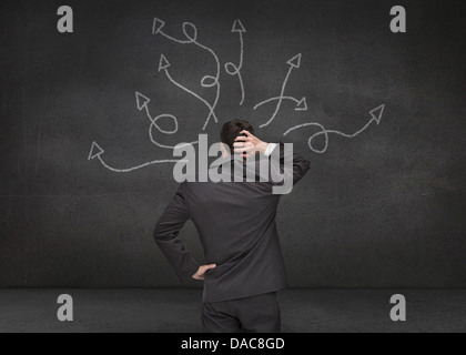 Doubtful businessman looking at arrows Stock Photo