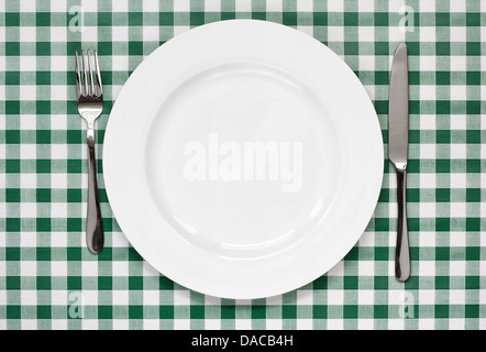place setting with empty plate, knife and fork on green gingham background popular symbol for diners and cafes Stock Photo