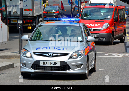 Front view blue lights on Metropolitan police car followed by police red Protection Command vehicle in Central London England UK Stock Photo