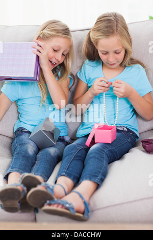 Twins unwrapping birthday gift sitting on a couch Stock Photo