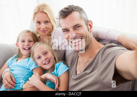 Man taking picture of wife and twins sitting on a couch Stock Photo