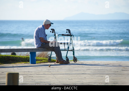 Man sat looking out to the Ocean on a warm sunny day. Stock Photo