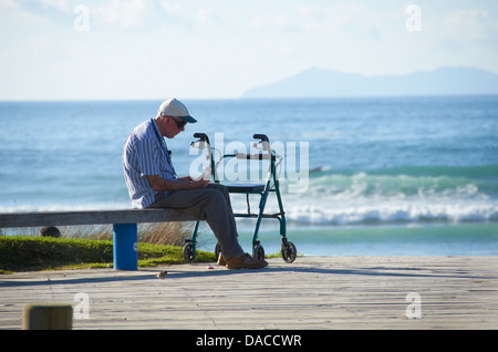 Man sat looking out to the Ocean on a warm sunny day. Stock Photo