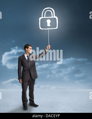 Businessman holding a floating padlock Stock Photo