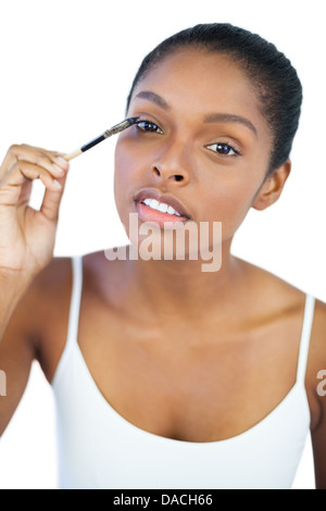 Dark haired woman putting on mascara Stock Photo