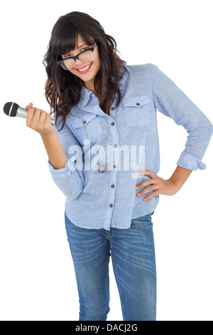 Cute woman with her hand on hip holding microphone Stock Photo