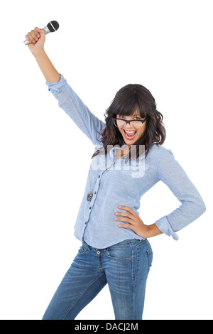 Happy brunette with her hand on hip holding microphone Stock Photo
