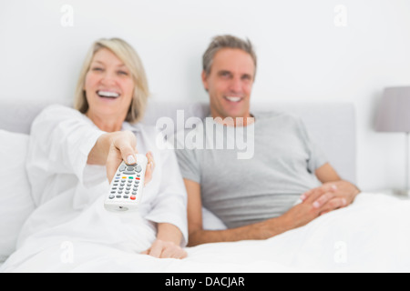 Laughing couple watching tv in bed Stock Photo