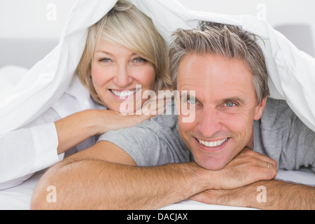 Couple smiling under the covers Stock Photo