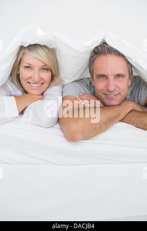 Attractive couple smiling under the covers at the camera Stock Photo