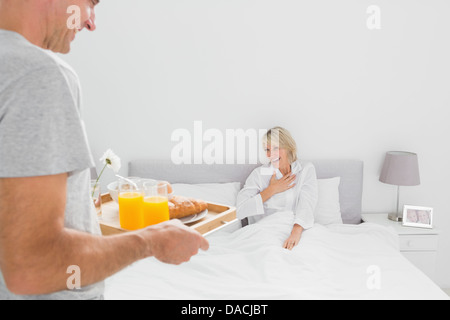 Man bringing breakfast in bed to his partner Stock Photo
