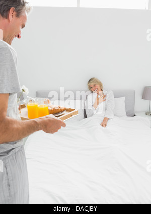 Man bringing breakfast in bed to his surprised partner Stock Photo