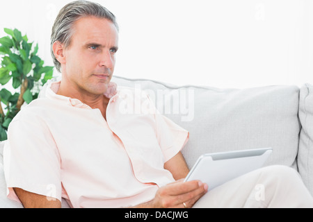 Man relaxing on his couch using tablet pc Stock Photo